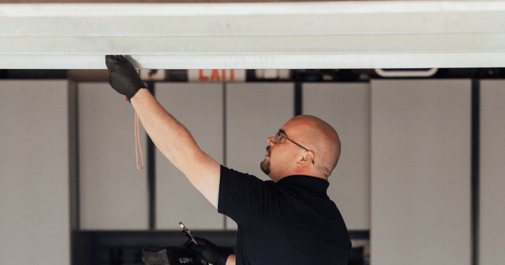 Man inspects garage door with safety gloves.
